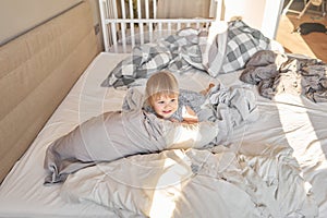 change of bed linen. A happy one-and-a-half-year-old girl helps and has fun and smiles while in a bright apartment