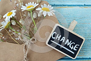 Change, handwritten word with chalk on small blackboard with old-fashioned envelope and flowers on wooden table