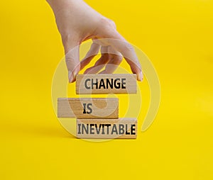 Change is Inevitable symbol. Wooden blocks with words Change is Inevitable. Beautiful yellow background. Businessman hand.