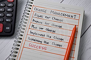 Change Management write on a book with keywords  wooden table
