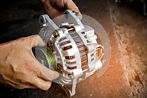 Change new car alternator with hand in the garage or auto repair service center, as background automotive concept. Dark tone photo