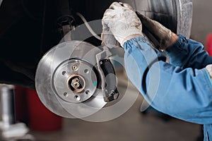 Change the old drive to the Brand new brake disc on car in a garage. Auto mechanic repairing .