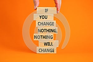 Change symbol. Wooden blocks with words `If you change nothing, nothing will change`. Businessman hand. Beautiful orange