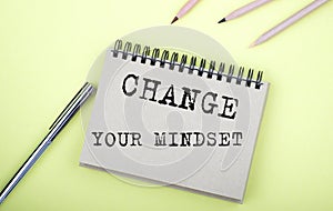 Change Your Mindset text on the notebook with pen on yellow background