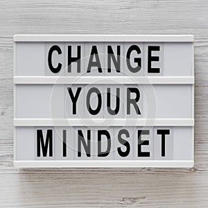 `Change your mindset` words on a lightbox on a white wooden background, top view. Overhead, from above, flat lay