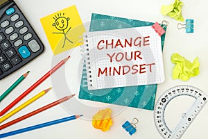 CHANGE YOUR MINDSET is written on a notepad on an office desk