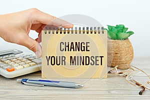 CHANGE YOUR MINDSET is written on a notepad on office desk