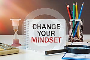 CHANGE YOUR MINDSET is written on a notepad on an office desk