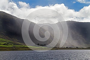 Changeable weather: rain and sun on lake in Irish mountains