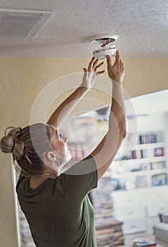 Changing the battery on a smoke alarm in an interior of a home