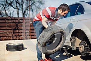 Changing a flat car tire in the backyard. Tire maintenance, damaged car tyre or changing seasonal tires