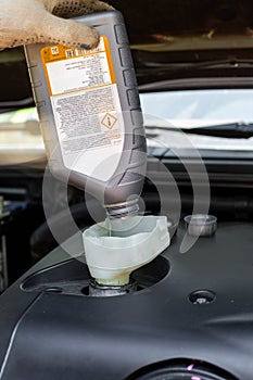 changing the oil in a car engine. A car mechanic pours engine oil through a funnel