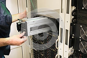 Changing the power module in the server room close-up. Working with equipment in the datacenter rack. Replacing the battery in an