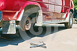 Changing a wheel or tire on an old vintage red van at outdoor car service