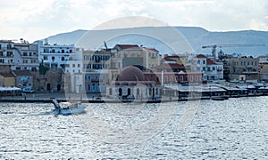 Chania Town Crete, Greece. View of outdoors cafe, seaside building. Motorboat sails in ripple sea