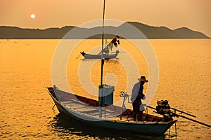 Chanthaburi, Thailand - February, 02,  2020 :Beautiful sunrise over sea with Silhouette of fishermen with yellow and orange sun in