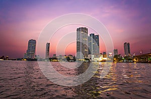 Chao Praya River in Bangkok, buildings and boats at sunset, Thailand