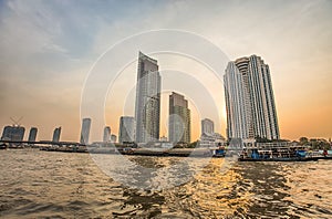 Chao Praya River in Bangkok, buildings and boats at sunset, Thailand