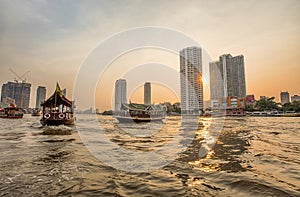 Chao Praya River in Bangkok, buildings and boats at sunset, Thailand