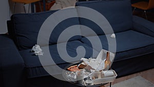 Chaos in empty living room with food garbage on table