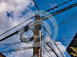 Chaotic electrical supply cabling on a pole on a street in Kampot, Cambodia