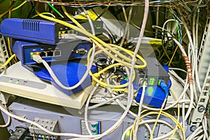 Chaotic interlacing of wires between modems, switches and Internet bridges. Rack with many network devices and cables. Box with