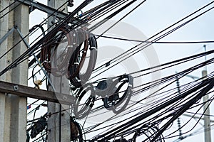 Chaotic Intertwining mess of electricity power lines on pole in Thailand