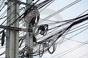 Chaotic Intertwining mess of electricity power lines on pole in Thailand
