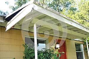 Chaotic looking front porch sagging rotting wood exterior light on red front door