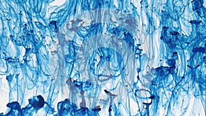 Chaotic movement of drops of blue paint in water. Abstract