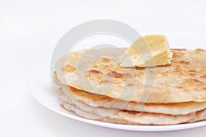 Chapatti, tortilla, fried in oil in a pan. finished dish. a piece of butter lies on fried flat cakes