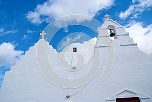 Chapel building architecture detail in Mykonos, Greece. Church bell tower and dome with crosses. White church on cloudy