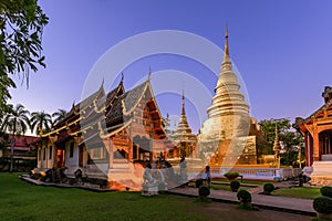 Chapel and golden pagoda at Wat Phra Singh Woramahawihan in Chiang Mai at twilight or night with stars in sky