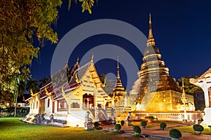 Chapel and golden pagoda at Wat Phra Singh Woramahawihan in Chiang Mai at twilight or night with stars in sky