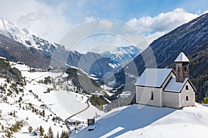 Chapel on a hill in a snowy alp valley