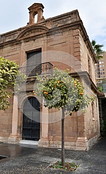 Chapel in the port of Malaga, trees with tangerines, stone building, Spain