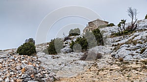 The chapel Saint-Pilon is on the mountain in cloudy weather, clouds over a valley, a dry grass, mountain over grotto of