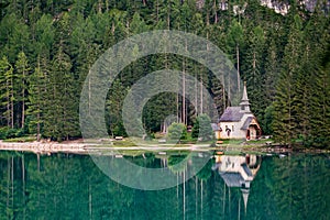 Chapel and trees are reflected in the water of Lake Braies