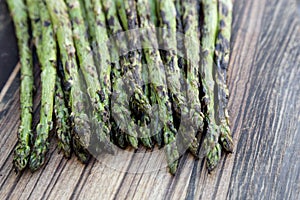 Char grilled asparagus on a wood background.