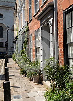 Characterful historic houses with flower pots on the pavement, on Wilkes Street in Spitalfields, East London.