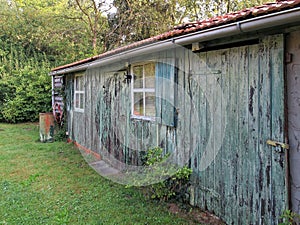 Characterfull shed in garden with old flaky grey-green paint