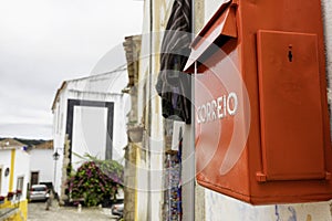 Characteristic Correio Box in english: Mail Box in a little village in Portugal. Red mail box against a white and yellow