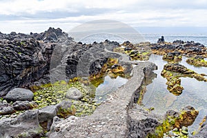 Characteristic volcanic formations next to the sea forming natural pools and water diversions photo