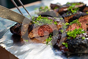 Charbroiled steak being cut over foil table