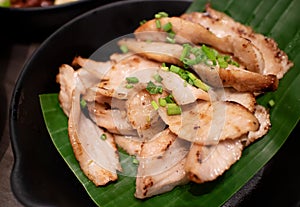 Charcoal-boiled pork neck, serving on banana leaf and black ceramic plate. Ready to eat in restaurant. North-east Thai traditional