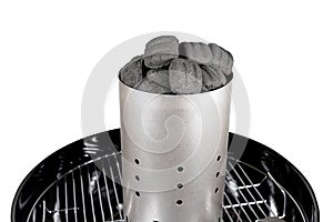 Charcoal briquette in the starter on the grill grid