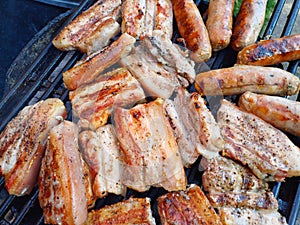 Charcoal grilled out door pork belly and homemade sausages on a barbecue grill