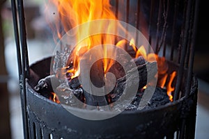 charcoals aflame in an upright chimney starter