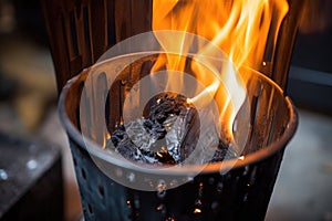 charcoals aflame in an upright chimney starter