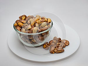 Charcole rosted cashew nut on the glass bowl with white background,cashew nuts are looks very natural without peal the skin with photo